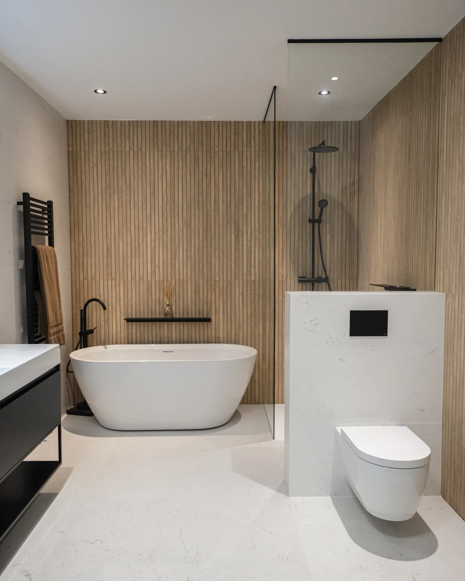 Badkamer met vrijstaand bad, houtlook wand en hangtoilet